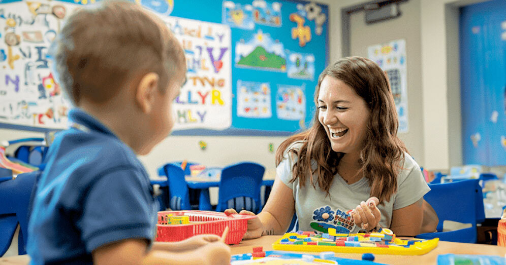 ABA therapist using colorful learning materials to engage with a child in a classroom setting.